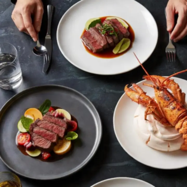 An elegant trio of signature dishes from Theflopand Flame arranged on a dark table.